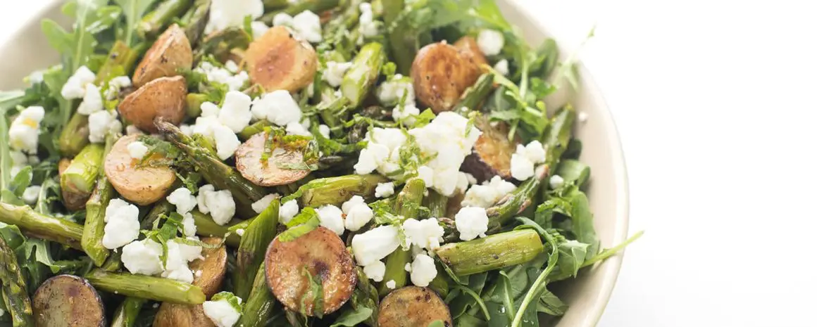 An arugula salad with roasted potatoes and goat cheese.