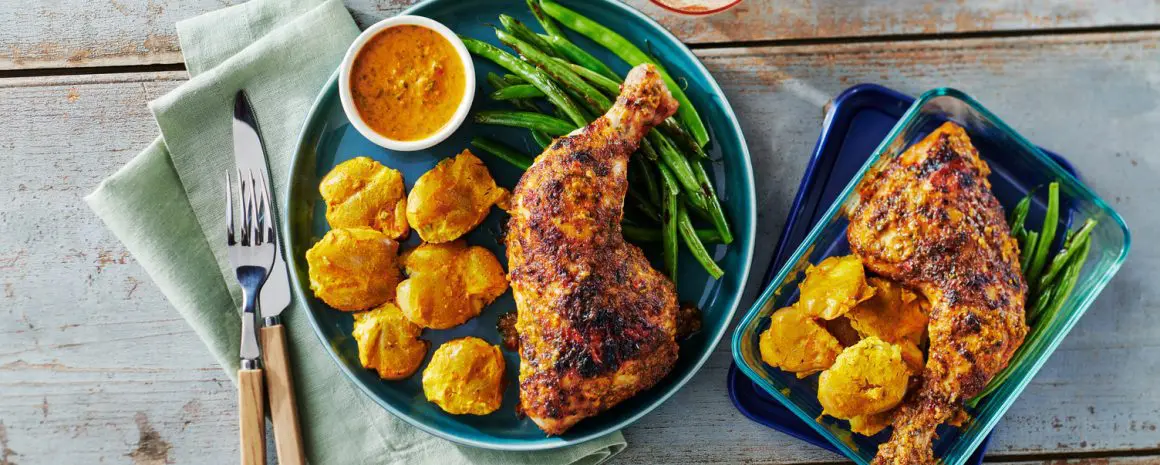 A plate of piri piri chicken and green beans with little potatoes.