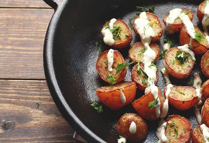 Crispy potatoes with vegan ranch dressing in a skillet.