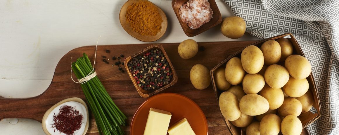 Ingredients on a cutting board like Little Potatoes, butter, chives, and pink salt.