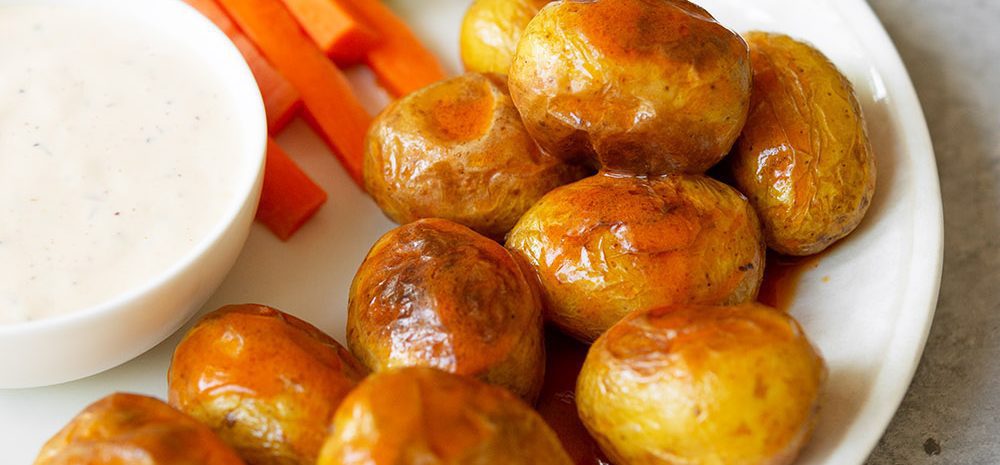 A plate of crispy little potatoes, carrots, and celery with dips.