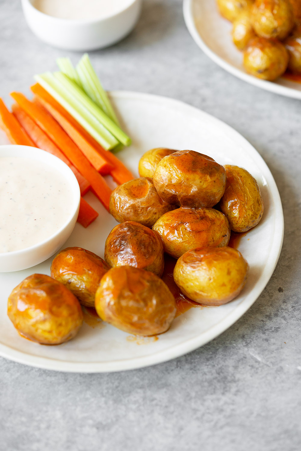 A plate of crispy little potatoes, carrots, and celery with dips.