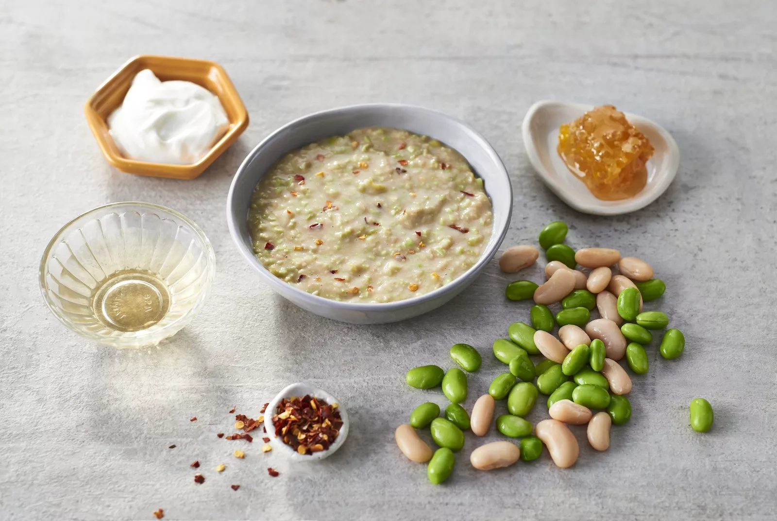Smashed Potatoes with Edamame and White Bean Dip_The Food Group_Web Res Some edamame and white bean dip with ingredients around it in a cute little bowl.