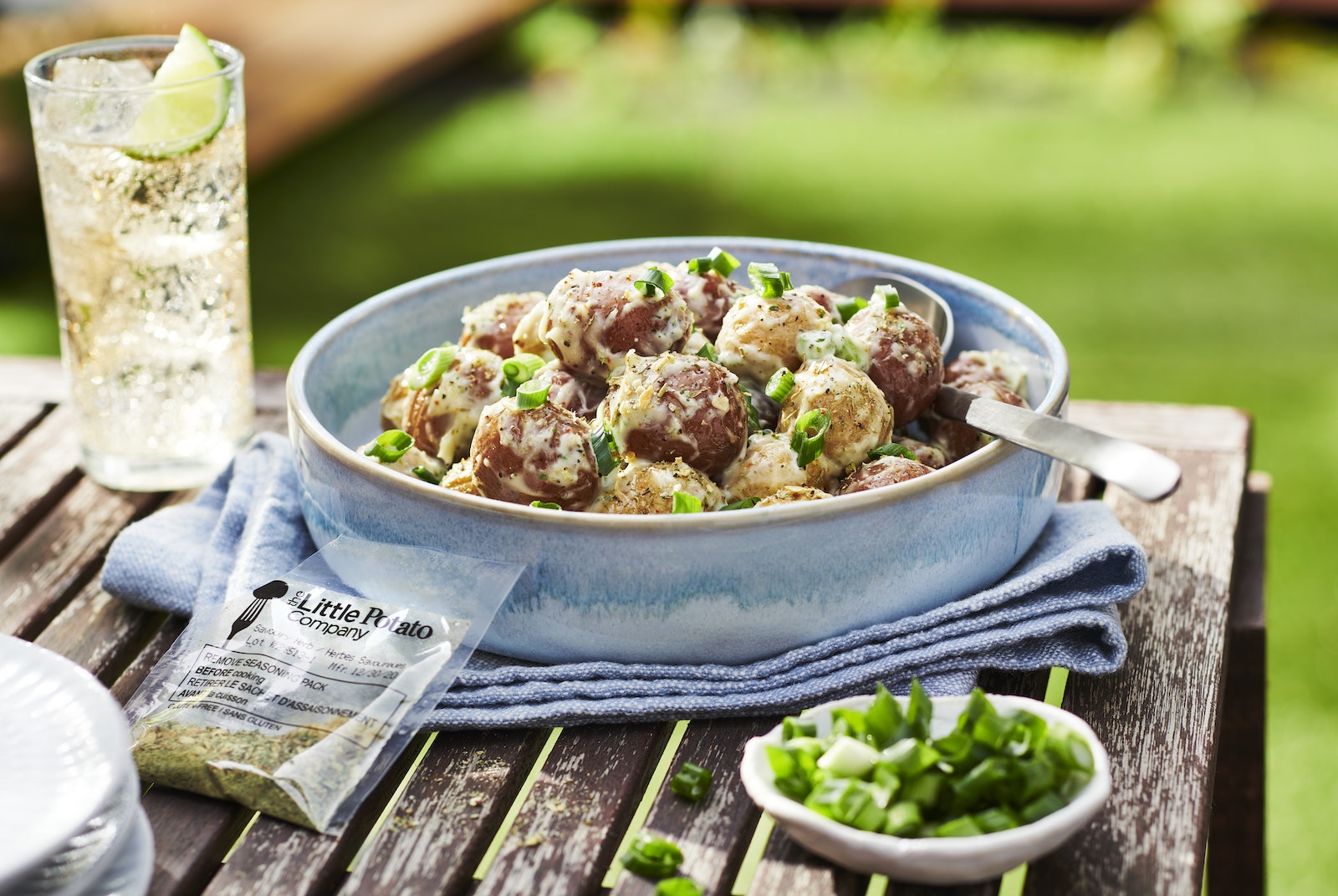 An easy to make potato salad in a blue bowl with a refreshing drink nearby.