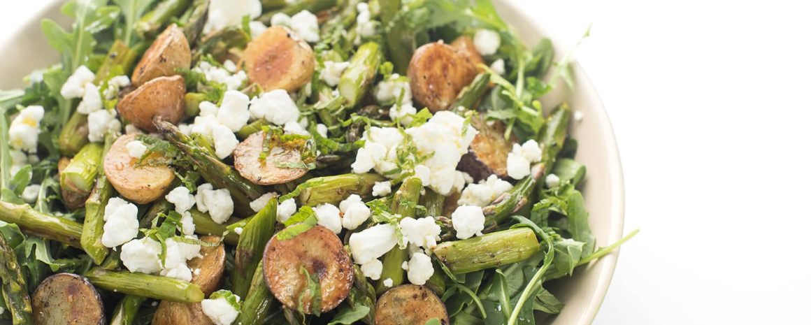 An arugula salad with roasted potatoes and goat cheese.