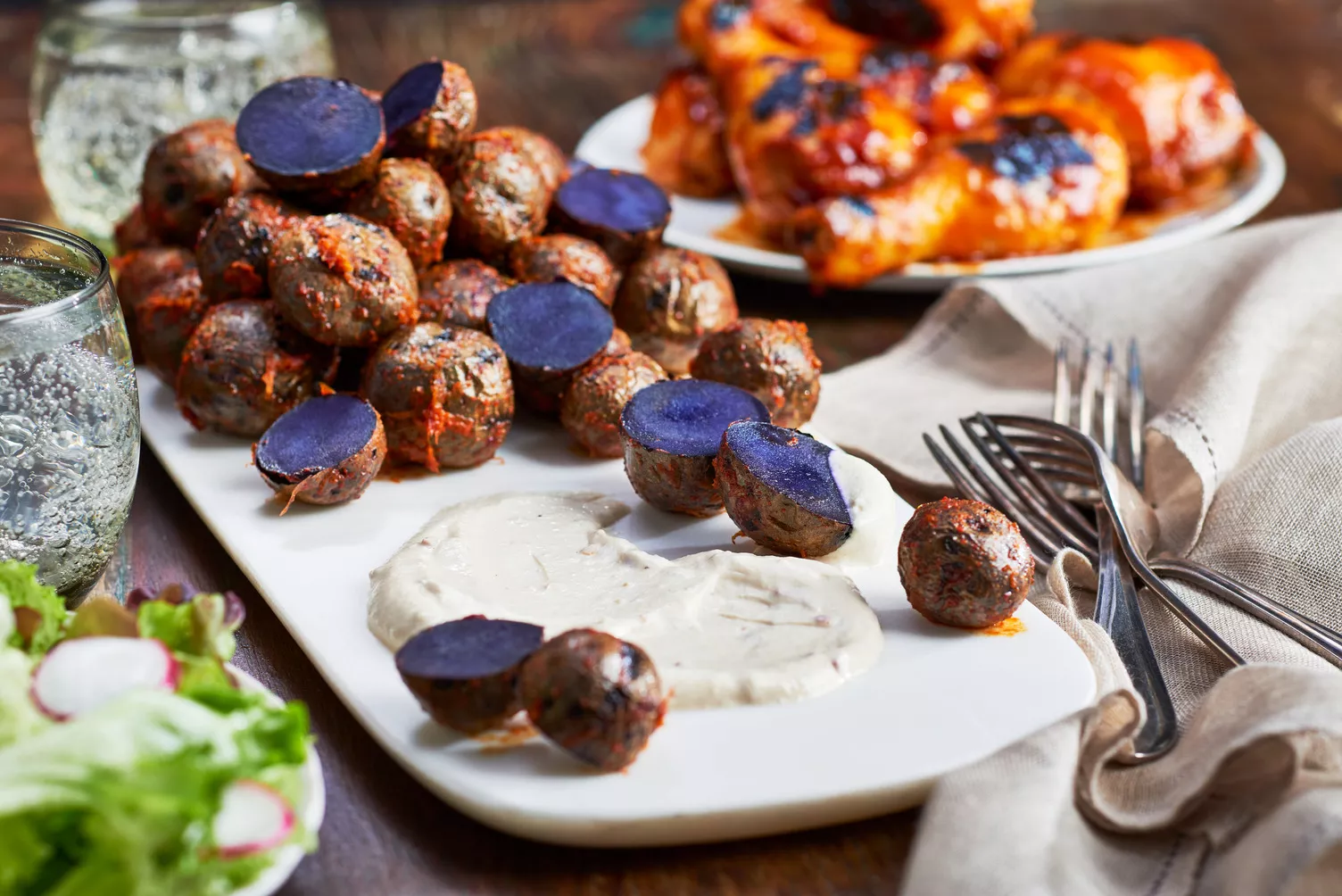 Barbecue-Potatoes-with-Lime-Chili-and-Yogurt-Sauce_The-Food-Group_Web-Res-2 A plate of brilliantly purple little potatoes with crema.