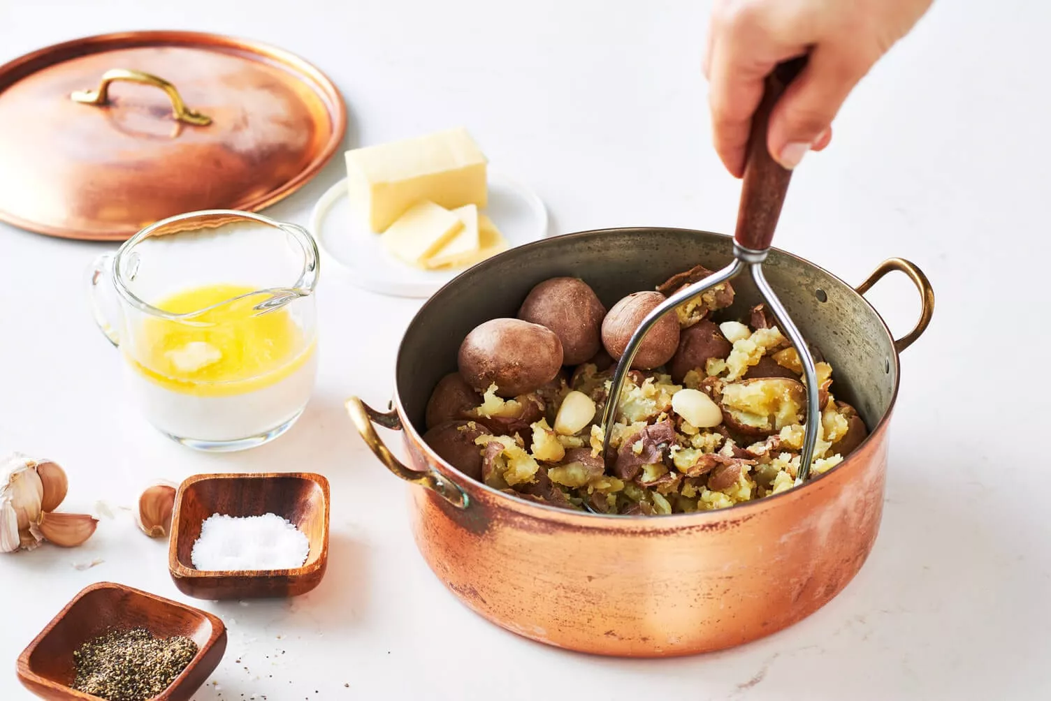 A nice big pot of boiled potatoes that are being mashed.