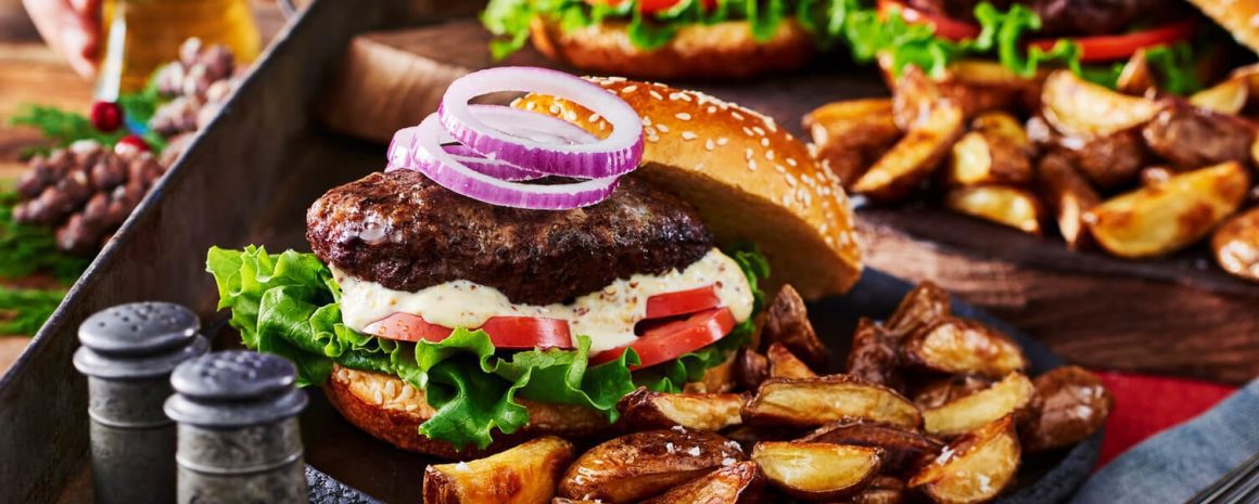 Burgers and mini wedges on a sheet pan.