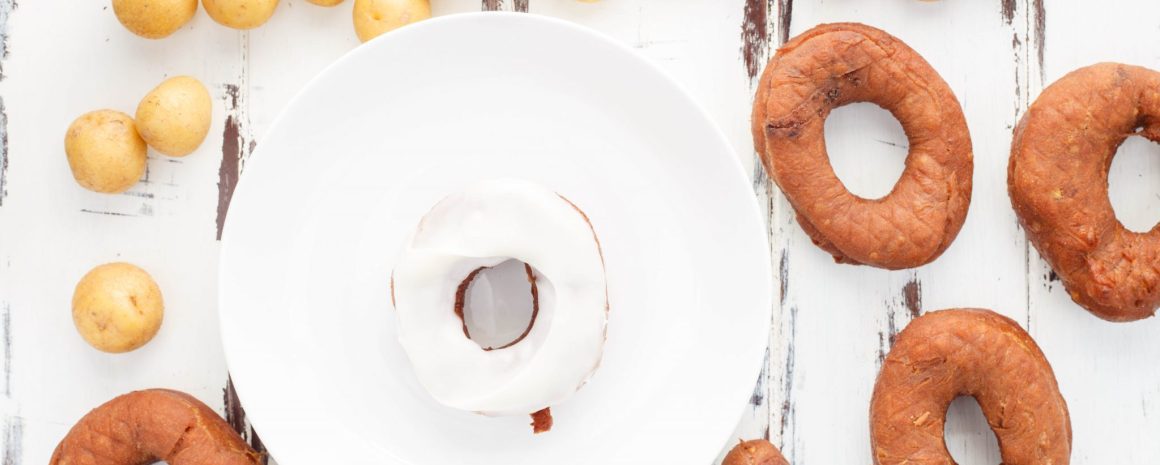 Chocolate potato doughnuts on a plate and a table.