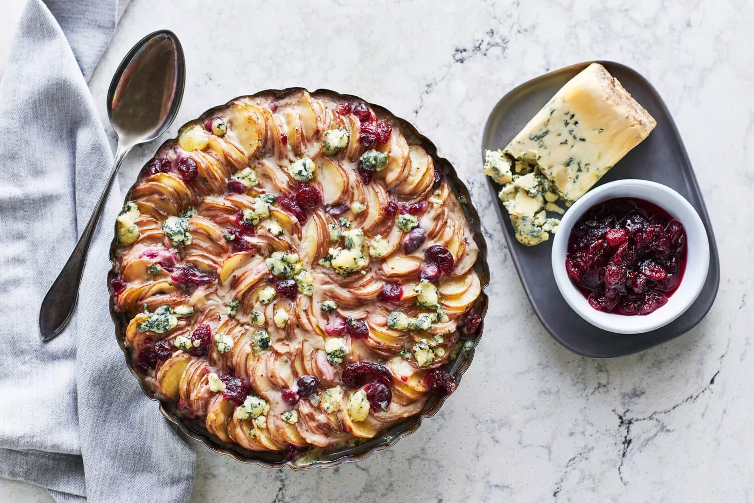 Cranberry-Stilton-Scalloped-Potatoes_The-Food-Group_Web-Res-1 A nice pie dish full of beautifully arranged scalloped potatoes with cranberry sauce and stilton cheese on top.