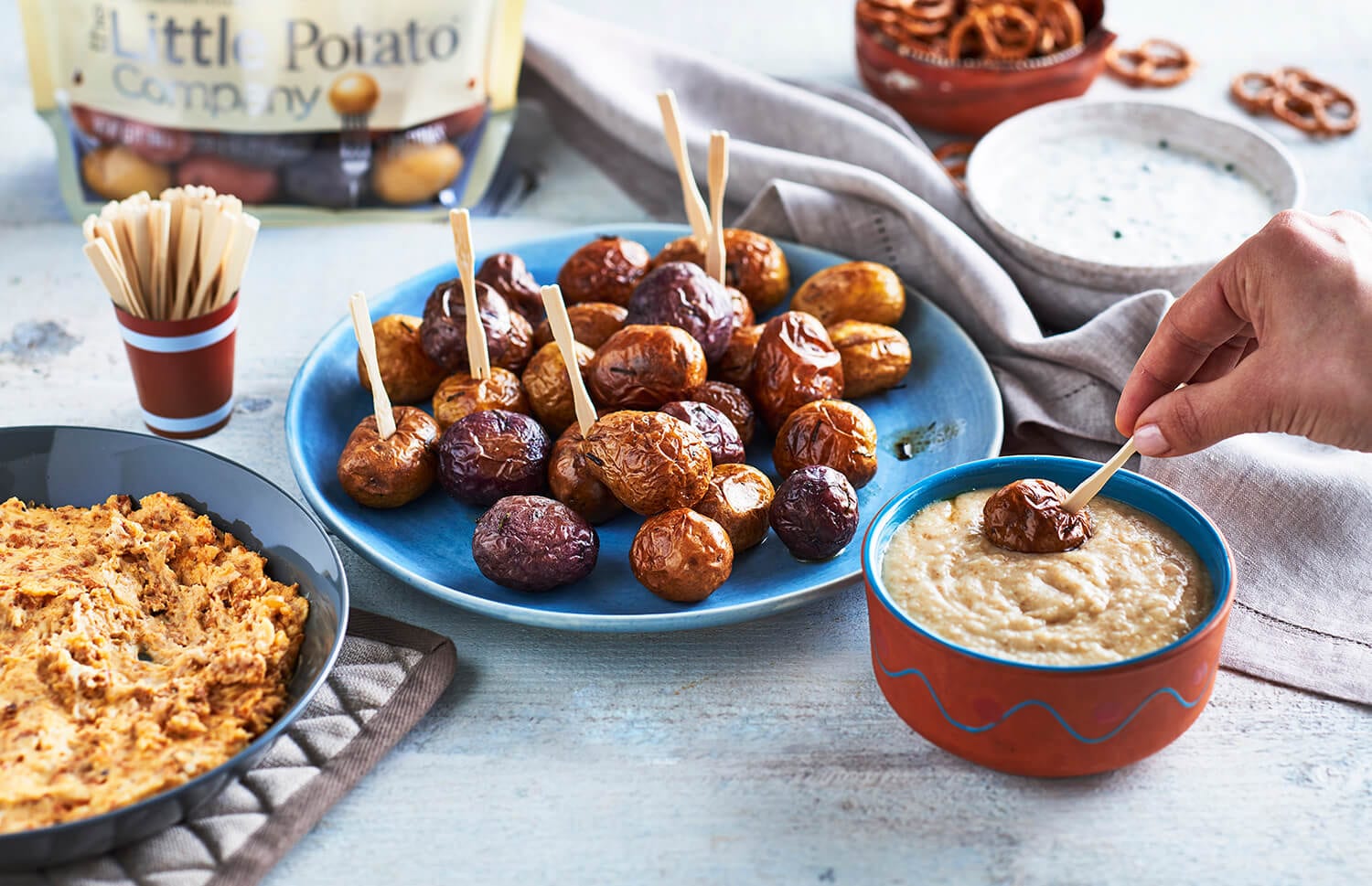 A plate of potatoes with toothpicks in them with dips on the side.