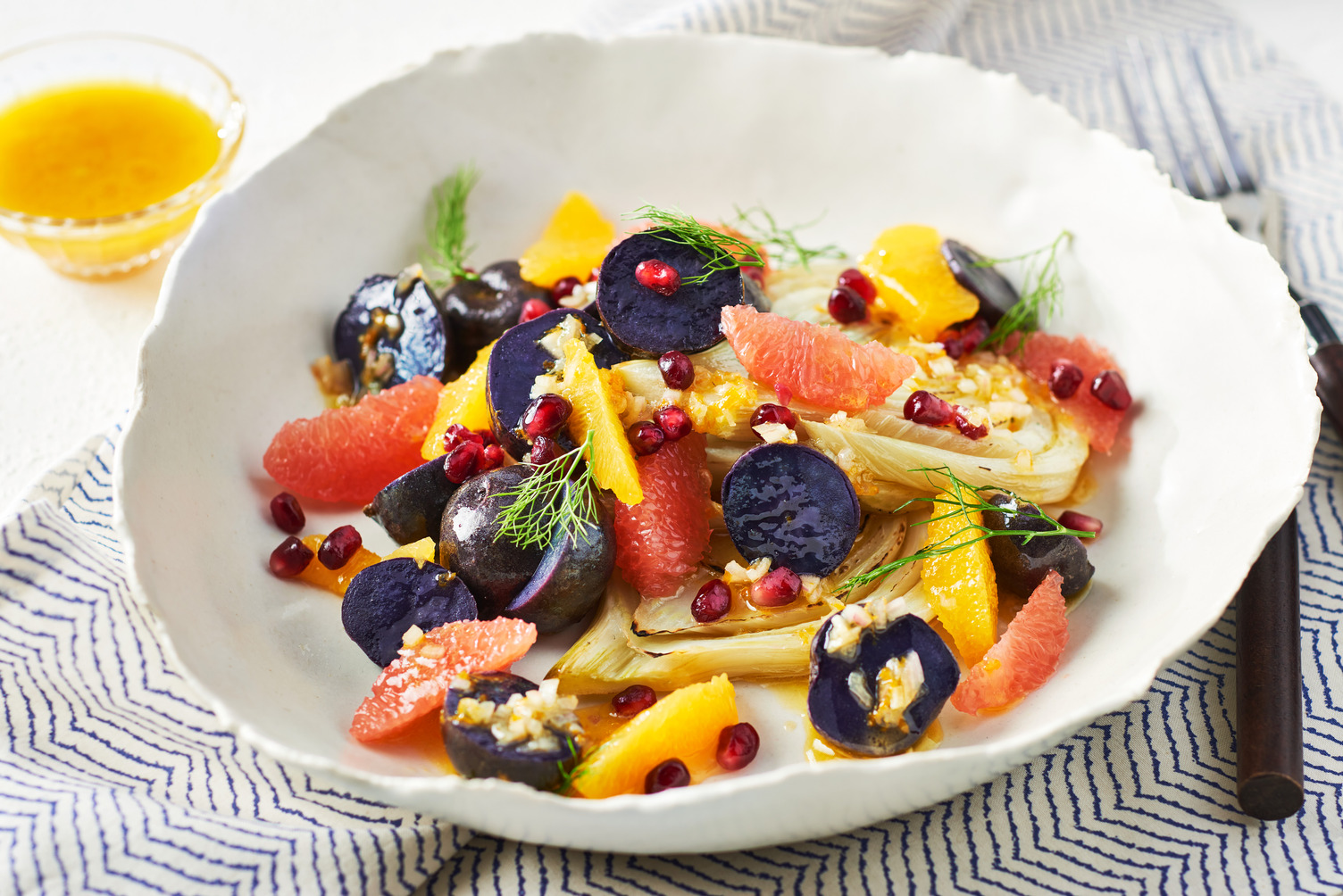 A bowl of little potatoes with fennel and colourful fruits and veggies.