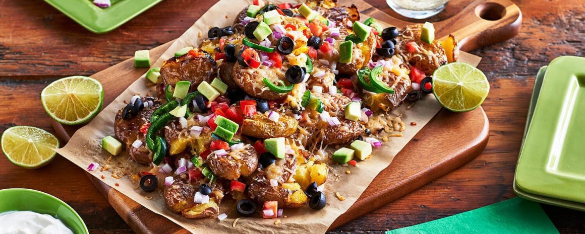 A parchment paper lined cutting board of fully loaded nachos.