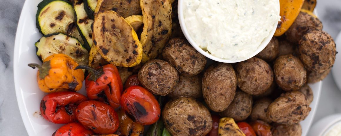 A platter of grilled veggies with some lemon feta dip