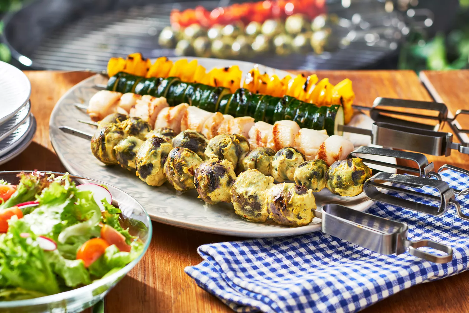 Grilled-Veggie-and-Scallop-Skewers_The-Food-Group_Web-Res-2 Three grilled kebabs with scallops, little potatoes, and veggies.