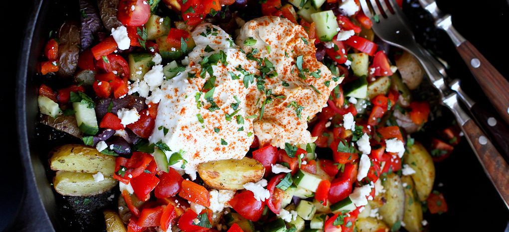 Mediterranean roasted potato nachos in a cast iron skillet.