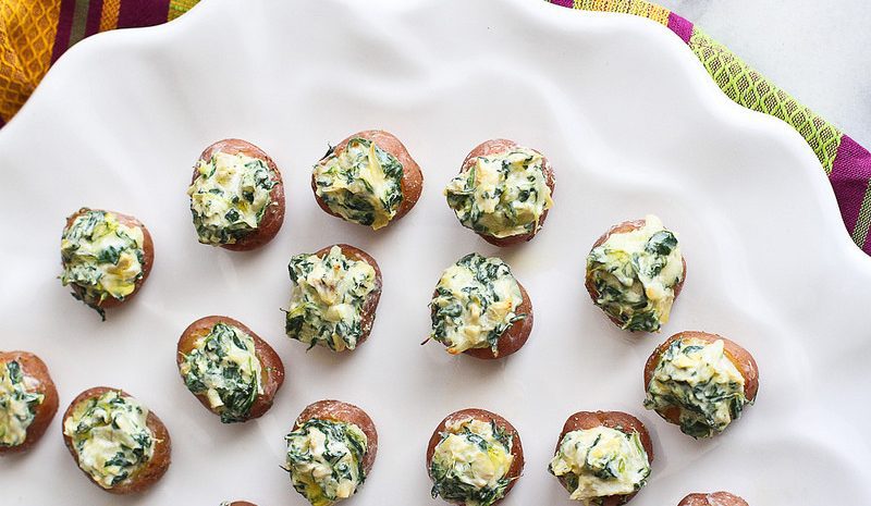 A plate of mini spinach and artichoke stuffed potatoes.