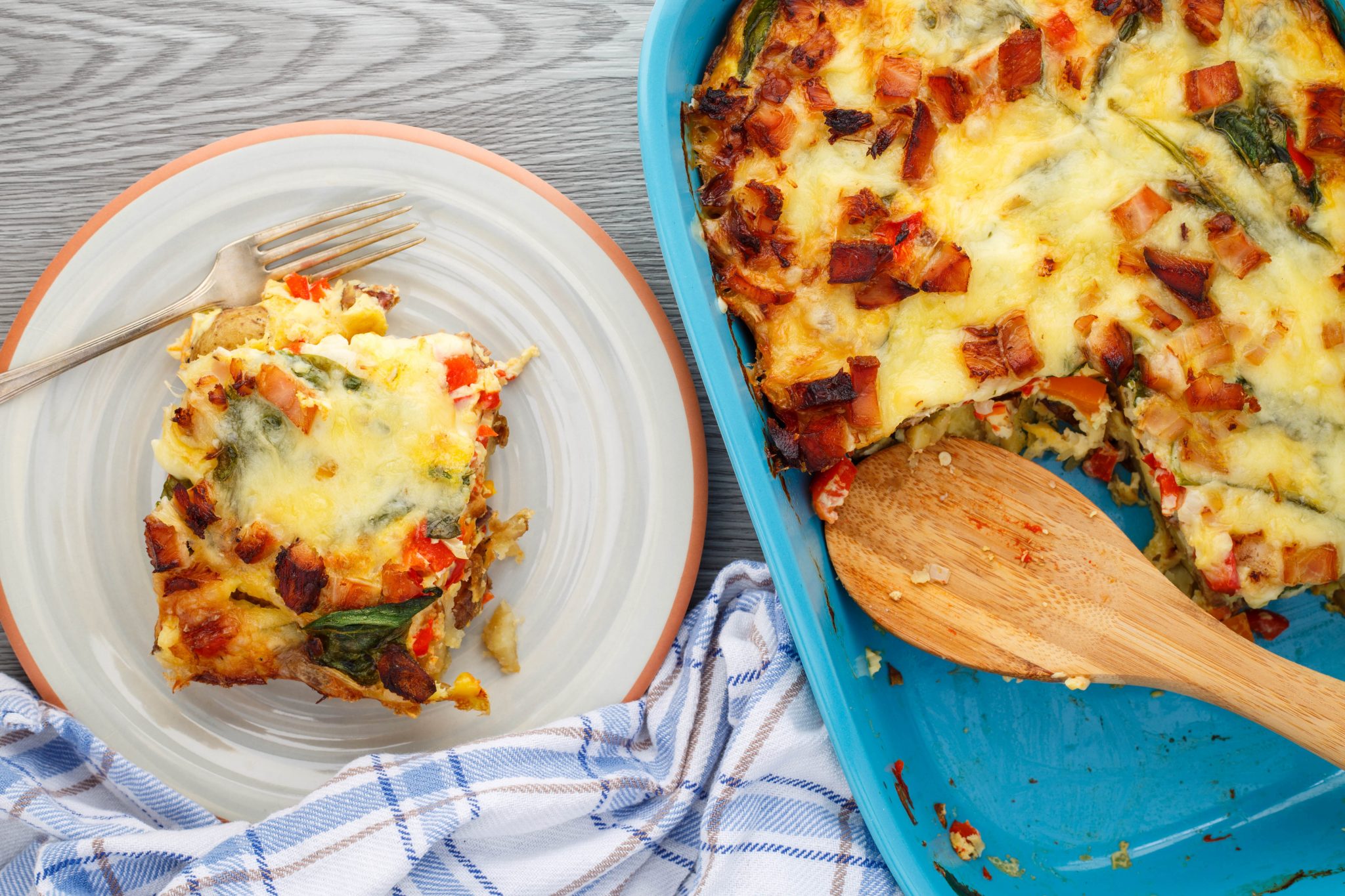 A baking dish with a plate next to it. Both have very delicious looking breakfast casserole on them.