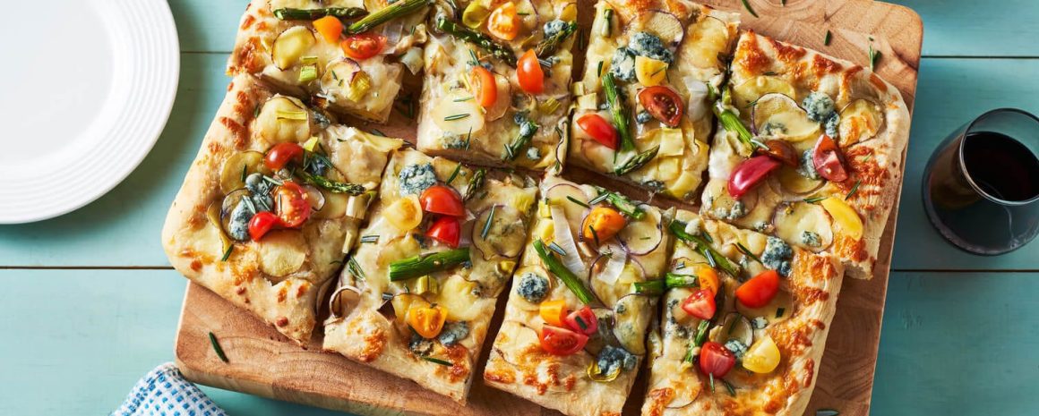 A lovely cutting board with a beautiful array of potato pizza on top.