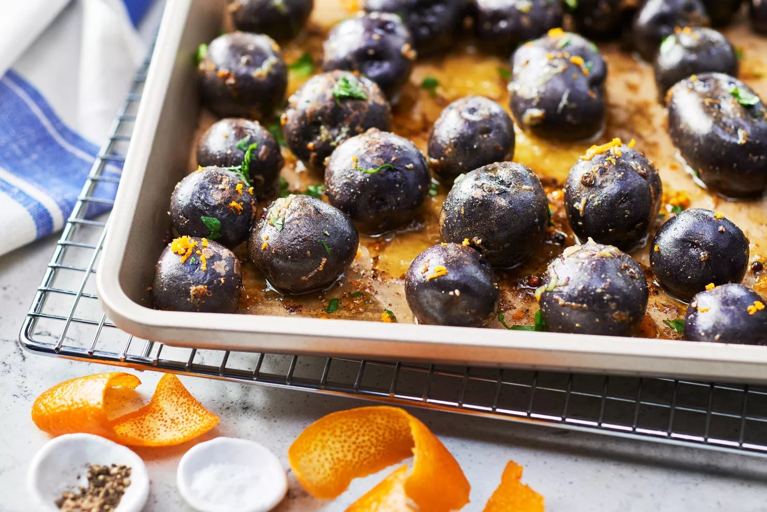 Roasted-Potatoes-with-a-Twist_The-Food-Group_Web-Res-3 Purple potatoes with some orange zest on a roasting tray.