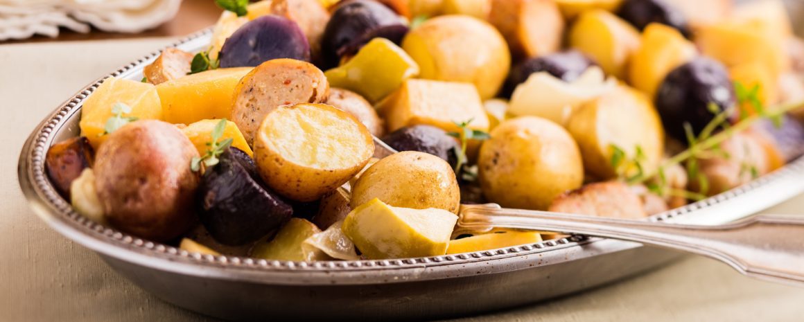 A plate of roasted veggies and sausages.