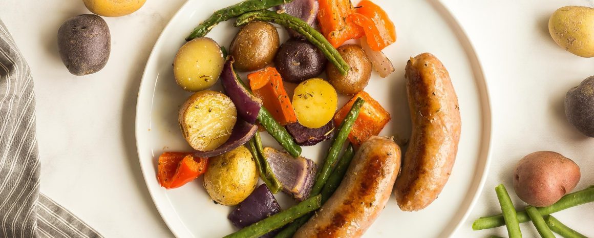 A plate of sheet pan sausages and potatoes.