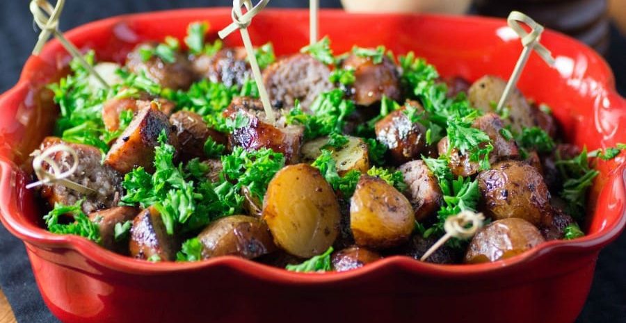 A serving dish of barbecue potato and sasauges.