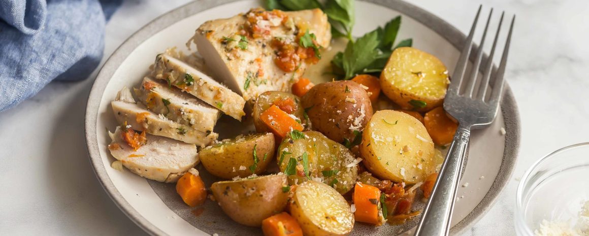 A plate of slow cooked chicken with potatoes and sun-dried tomatoes.