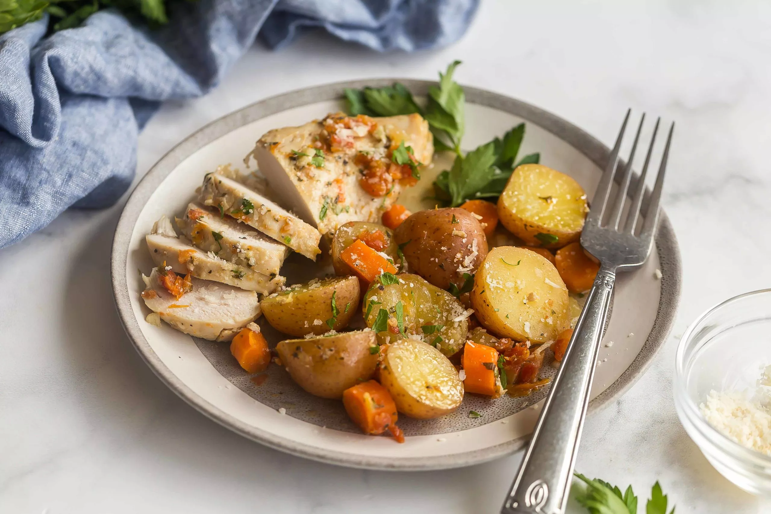 A plate of slow cooked chicken with potatoes and sun-dried tomatoes.