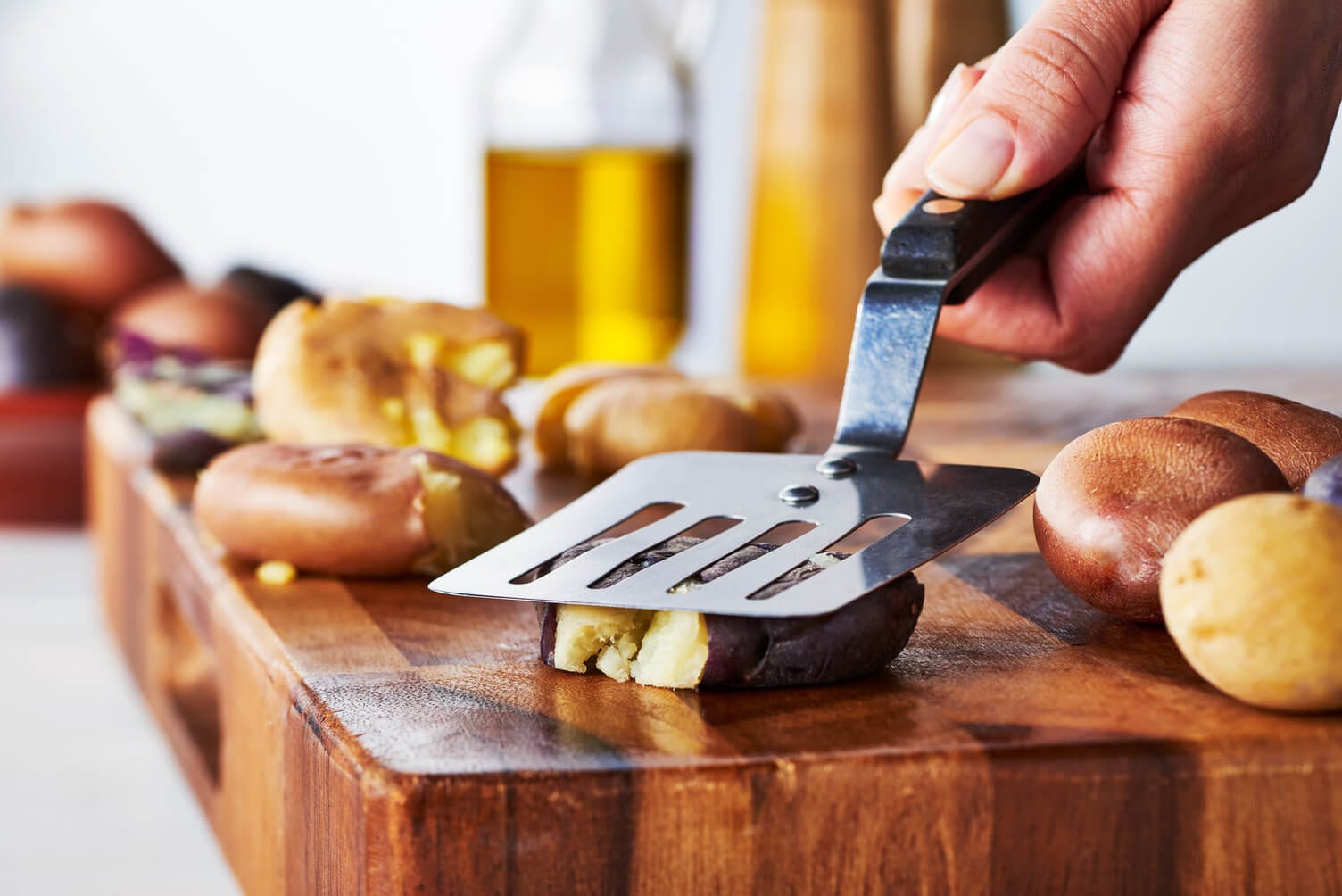 Smashing potatoes with a slotted spatula.