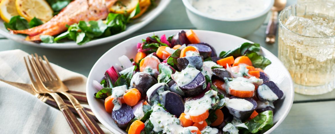 A bowl of steamy vegetables topped with dressing.