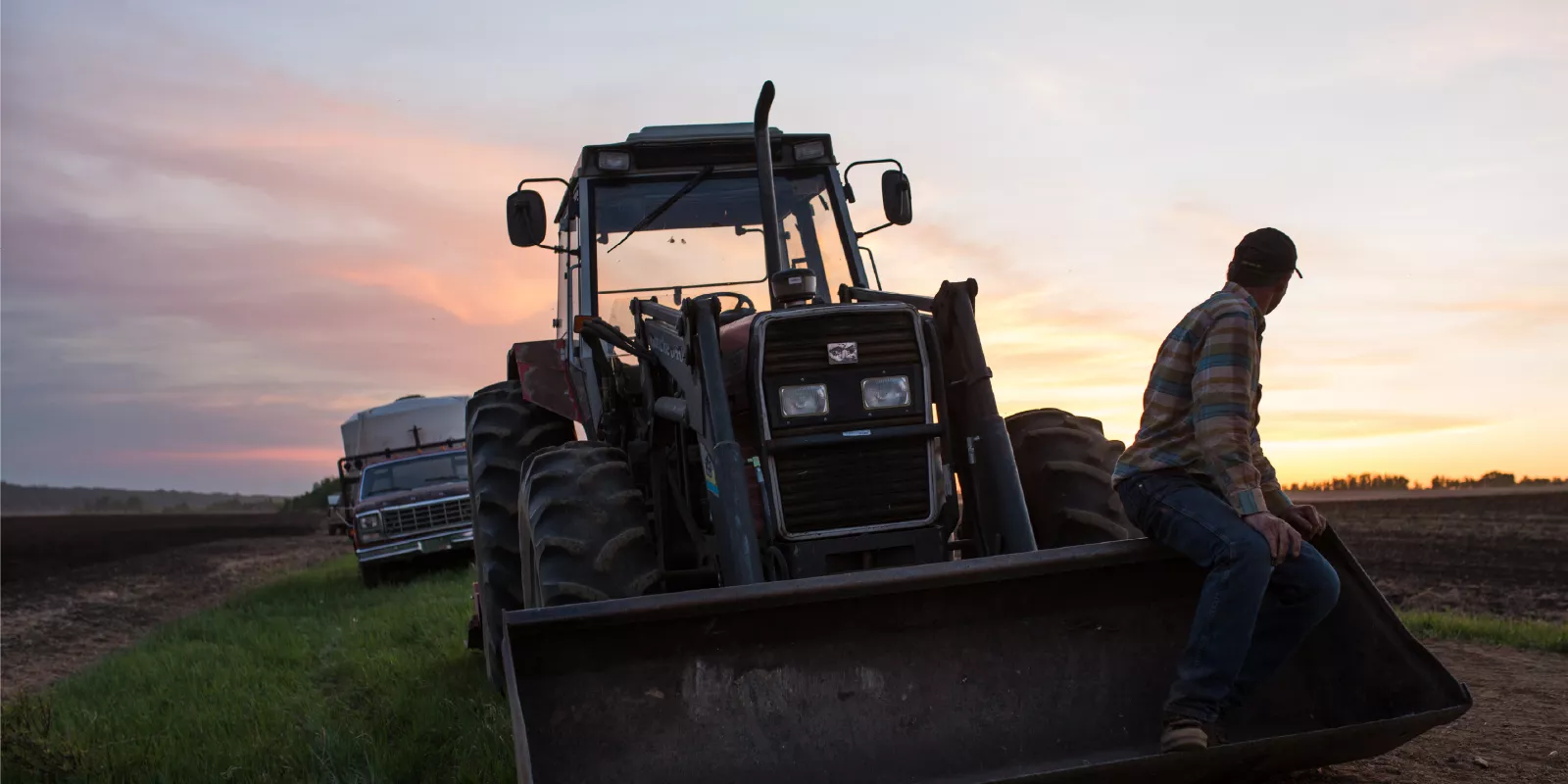 A farmer and his tractor in the potato field.