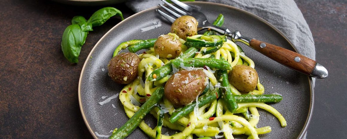 A plate of zucchini noodles with pesto and potatoes