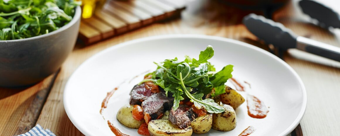 A plate of steak and Little Potatoes with Romesco sauce.