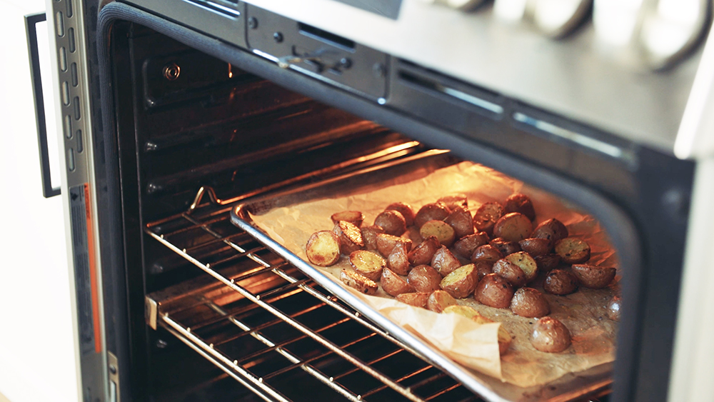 Little Potatoes on a parchment paper lined baking sheet in the oven.